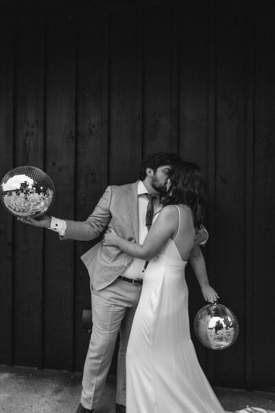 Couple kissing while both holding disco balls - New England Wedding Planner