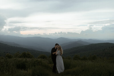 bride and groom hike on mountain top during golden hour on roan mountain