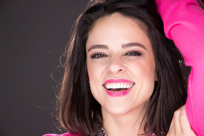 Caucasian woman smiling wearing pink lipstick and top
