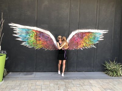 girl in front of angel wings mural
