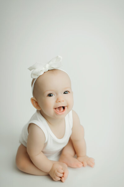 6 month old baby sitting on a white backdrop
