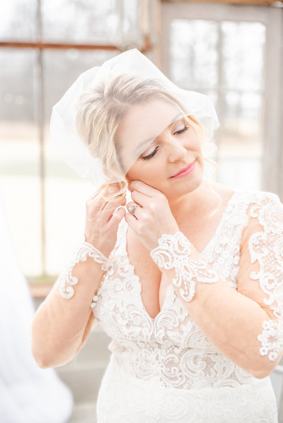 portrait of bride putting in her earrings on her wedding day