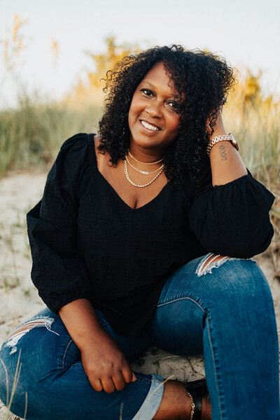Black artist on a beach in jeans and black shirt with curly hair