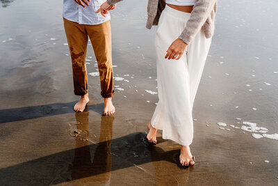 a couples feet and legs in focus walking on a beach in Oregon
