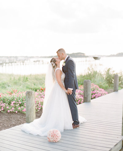 Bride and groom kiss on dock at Clarks Landing Yacht Club wedding