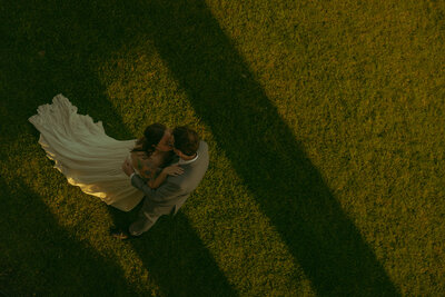 Man and woman romantically spin around, laughing in the middle of a  flowery field