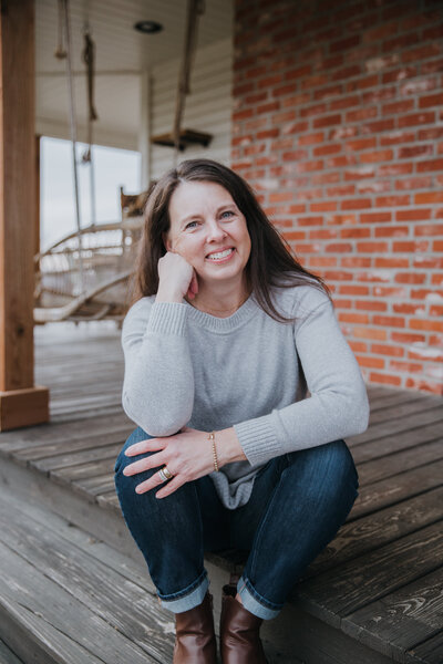 Rachel Sanford sitting on farmhouse porch in jeans