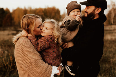 föräldrar håller varsitt barn i famnen under familjefotografering under hösten utomhus i halmstad