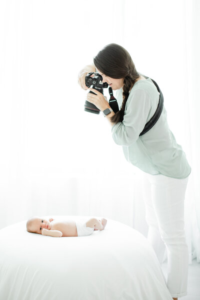 Newborn photographer, Kristin Wood, takes overhead shot of newborn baby on a bed