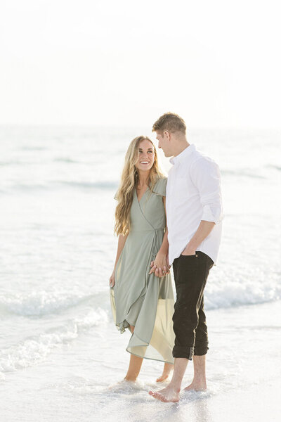 engaged couple walking on the beach