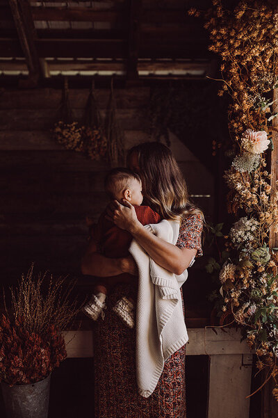 Maman et son bebe dans les bras entoure de fleurs