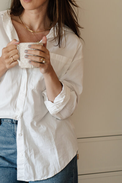 A young woman holding a white mug. Representing someone who goes to counseling or therapy for women in Brooklyn, New York.