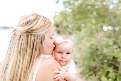 Infant looks over mother's shoulder during newborn family photoshoot.