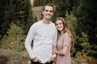 Rachel and her husband standing and smiling with trees in the background