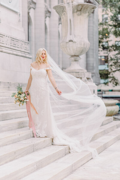 Bride with cathedral veil on steps of NYC public library