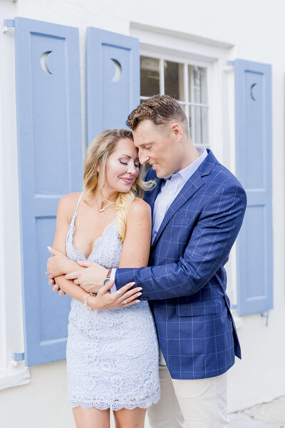 couple standing in front of blue and white house in Charleston for engagement session