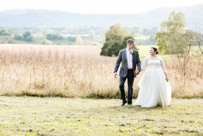 Camile and Austin walking in a field on their wedding day