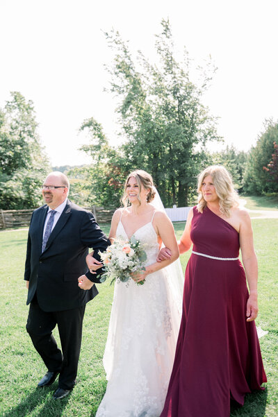Bride being walked down the aisle by parents captured by Niagara wedding photographer