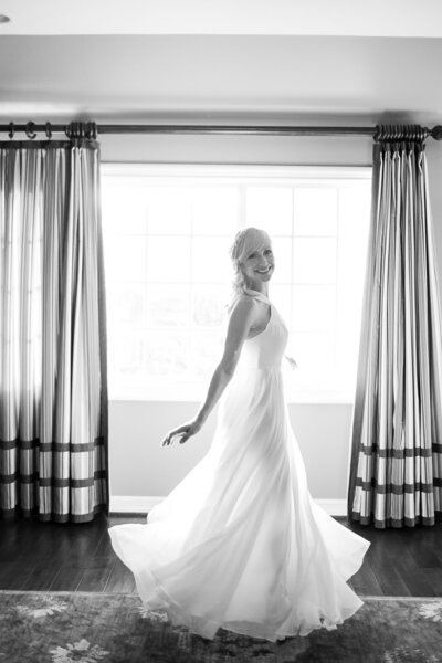 Happy bride twirls in her wedding gown on her wedding day