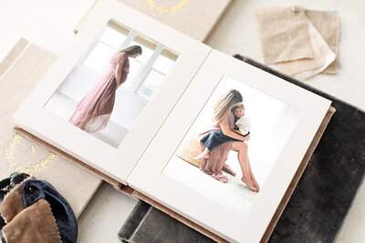 A photo of heirloom albums, with one opened to a picture of a pregnant mom on one side and a mom holding her daughter on her lap on the other side.