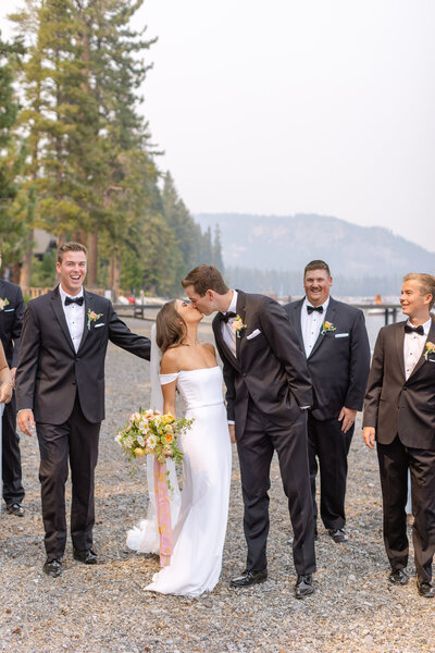 bride and groom kissing in front of lake