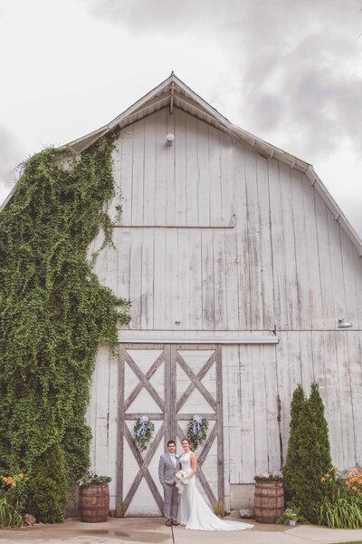 A couple standing in front of their barn wedding venue.