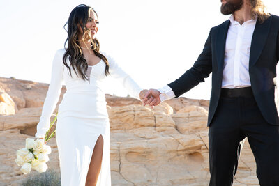 An Austin-based wedding photographer captures a bride and groom holding hands in the serene desert.