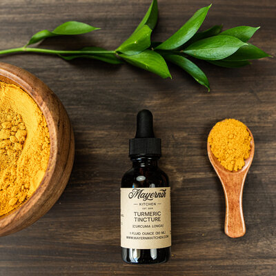 Bottle of turmeric tincture styled with ground turmeric and greenery