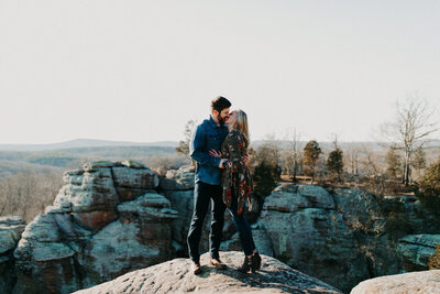 man and woman kissing while standing on rocks