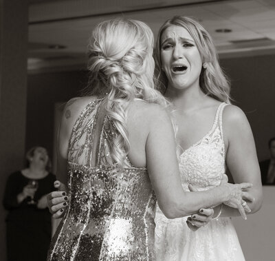 A photo of a bride crying while hugging someone.