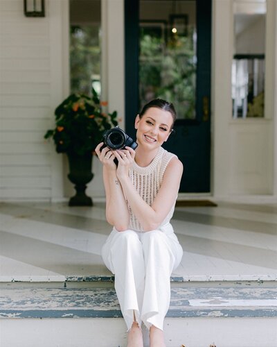 Allison sitting on porch steps holding camera