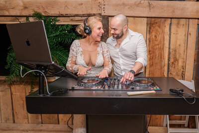 A bride and groom at their wedding reception playing the DJ turntable by JoLynn Photography