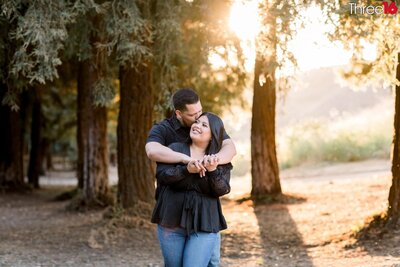 Engaged couple hold hands and smile at each other on a trail  during a Redwood Grove engagement shoot in Yorba Linda