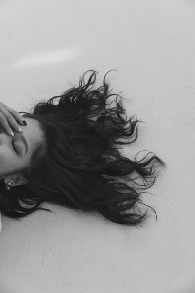 Laying on the ground with dark, curly hair
