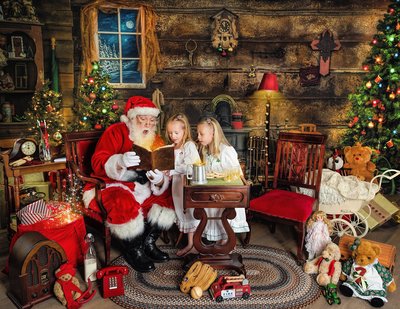 Santa looking at a book with two young girls in pajamas