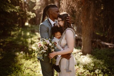 Couple in the mountains with their kid during their elopement