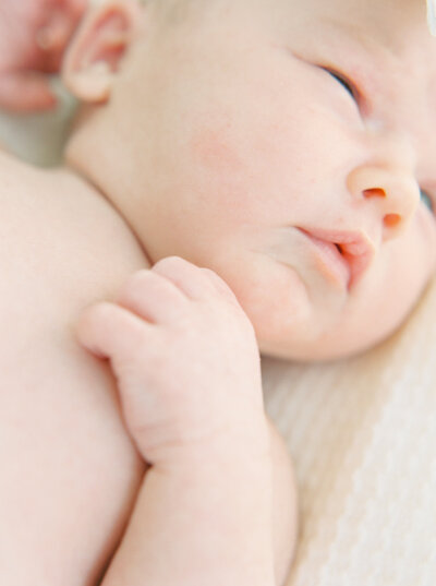 Newborn baby laying on bed.