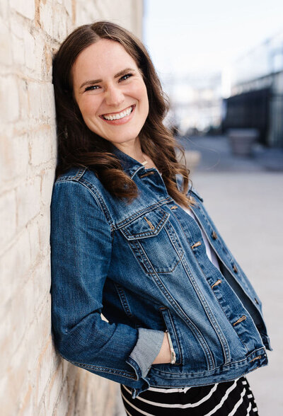 woman leaning against brick wall looking and smiling