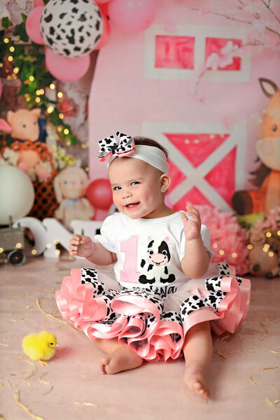 Sweetie posing in cow print for her first birthday cake smash