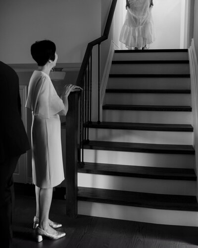 Bride walking down stairs for first look with mother.