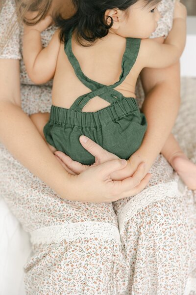 One year old boy in a forest green romper clings to his mother, indianapolis photographer