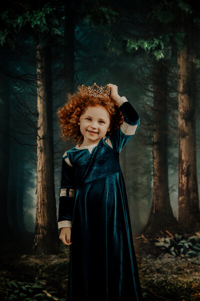 merida inspired princess holding a crown on her head wearing a blue dress