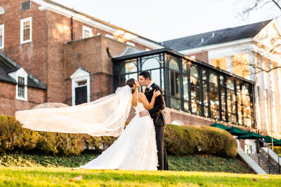 Couple kissing outside of BCC as wind blows the bride's veil, Baltimore wedding photography