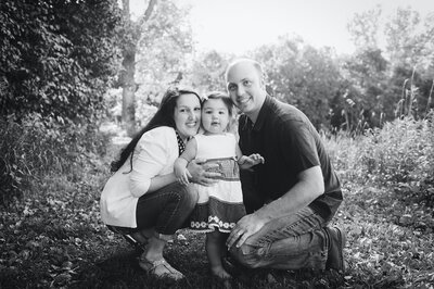 Mom and dad surrounding small daughter black and white picture