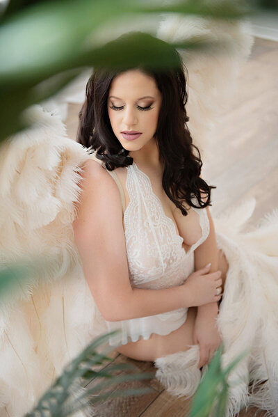 Woman posing in luxurious boudoir wings for brightly lit boudoir portrait