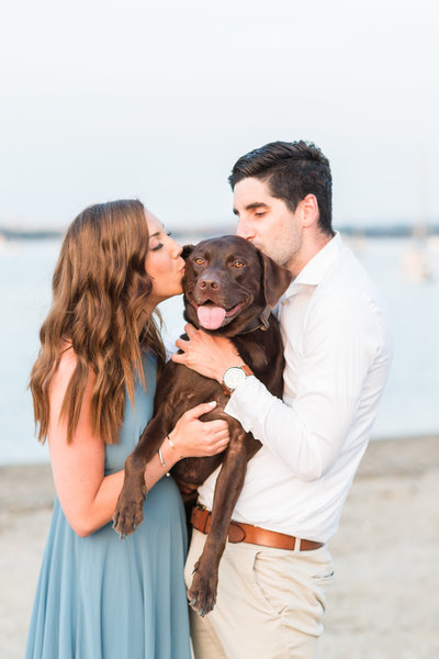 couple kissing their chocolate lab