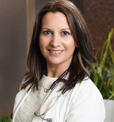 Engaging headshot of a Toronto-based healthcare professional, wearing a white lab coat and smiling confidently at the camera