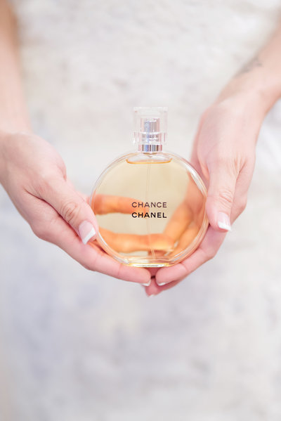 Bride holds a bottle of Chanel perfume on her wedding day