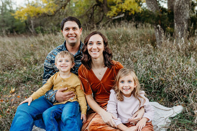 Parents and 3 boys smile for a picture while embracing the fall colors.