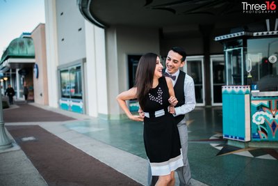 Groom to be surprises fiance from behind in front of a theater on Newport Island during photo shoot